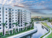 Thumbnail 1 of 25 - A white building with a red roof is situated next to a body of water.