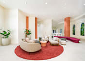 Thumbnail 10 of 25 - A living room with a red rug and a large chair.