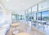 Thumbnail 15 of 25 - A modern living room with a white sofa and a glass wall.