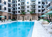 Thumbnail 21 of 25 - A large swimming pool in front of a multi-story apartment building.