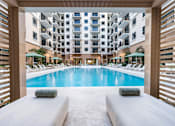 Thumbnail 22 of 25 - A large indoor swimming pool with a view of a multi-story building.