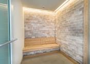 Thumbnail 18 of 25 - A wooden bench sits against a brick wall in a room.