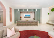 Thumbnail 12 of 25 - A modern living room with a grey sofa and a red rug.