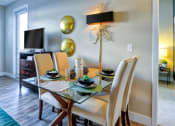 Thumbnail 4 of 25 - a dining room with a table and chairs and a television in the background