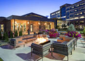 Thumbnail 19 of 25 - a patio with couches and a fire pit in front of a building