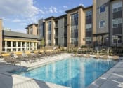 Thumbnail 3 of 25 - a swimming pool with chaise lounge chairs and a building in the background
