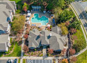 Thumbnail 1 of 40 - An aerial view of a residential area with houses, a swimming pool, and a parking lot.