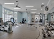 Thumbnail 21 of 40 - A spacious gym with a variety of equipment including treadmills, weights, and a bench press.