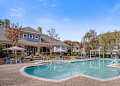Thumbnail 13 of 40 - A large swimming pool surrounded by a brick patio and lounge chairs.