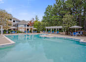 Thumbnail 10 of 40 - A large swimming pool surrounded by trees and a building.