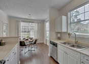 Thumbnail 33 of 40 - A kitchen with white cabinets and a dining table.