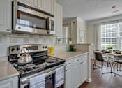 Thumbnail 34 of 40 - A modern kitchen with a stove, microwave, and a dining table.