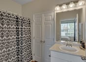 Thumbnail 35 of 40 - A bathroom with a sink, mirror, and shower curtain.
