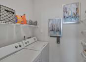 Thumbnail 38 of 40 - A laundry room with a washer and dryer and a painting on the wall.
