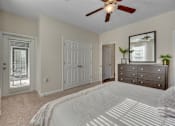 Thumbnail 29 of 40 - A bedroom with a white bedspread and a ceiling fan.