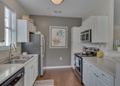 Thumbnail 37 of 40 - A kitchen with white cabinets and a black stove top oven.