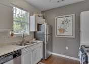 Thumbnail 36 of 40 - A kitchen with a refrigerator, sink, and cabinets.