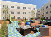 Thumbnail 23 of 28 - a patio with couches and tables in front of an apartment building