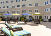 Thumbnail 26 of 28 - a large patio with chairs and umbrellas in front of a building