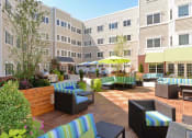 Thumbnail 21 of 28 - an outdoor lounge area with a yellow umbrella and apartment buildings in the background