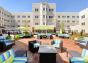 Thumbnail 24 of 28 - a patio with a firepit and lounge chairs in front of a building