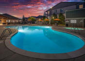 Thumbnail 22 of 47 - a swimming pool at dusk at a hotel with a sunset in the background
