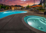 Thumbnail 23 of 47 - a swimming pool at dusk with umbrellas and a building in the background