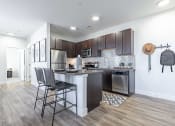 Thumbnail 11 of 30 - a kitchen with dark wood cabinets and a white island with three stools at RockVue, Broomfield, CO, 80021