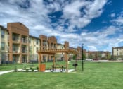 Thumbnail 17 of 28 - a picnic area in the middle of a grassy area with buildings in the background at Retreat at Shadow Creek Ranch Apartments, Woodburn, 77584