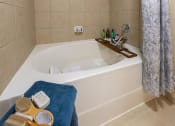 Thumbnail 24 of 28 - a bathtub with a wooden tray on top of it at Retreat at Shadow Creek Ranch Apartments, Woodburn, 77584