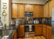 Thumbnail 21 of 28 - a kitchen with a stove a sink and a refrigerator at Retreat at Shadow Creek Ranch Apartments, Texas, 77584