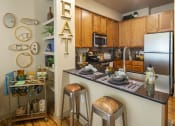 Thumbnail 15 of 28 - a kitchen with a counter top and stools at Retreat at Shadow Creek Ranch Apartments, Woodburn, TX, 77584