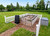 Thumbnail 19 of 24 - a garden with a raised garden bed and a fence at Eagles Landing Apartments, Everett, 98204