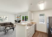 Thumbnail 14 of 22 - a living room with a couch and a kitchen with a sink at Sage Apartments, Everett, Washington
