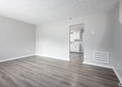 Thumbnail 10 of 16 - an empty living room with wood floors and white walls
