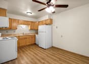 Thumbnail 2 of 9 - A kitchen with a white refrigerator, white stove, and wooden cabinets.