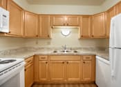 Thumbnail 1 of 9 - A kitchen with wooden cabinets and a white refrigerator.