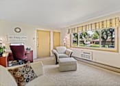 Thumbnail 4 of 9 - A living room with a couch, chair, and a window with a view of trees.