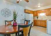 Thumbnail 9 of 9 - A kitchen with a table and chairs in the foreground and a white refrigerator in the background.