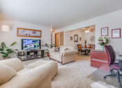 Thumbnail 8 of 9 - A living room with a white couch, a television, and a chair.