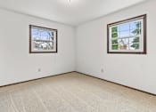 Thumbnail 22 of 33 - A room with two windows and carpeted floor.