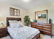 Thumbnail 5 of 9 - A bedroom with a bed, dresser, and mirror.