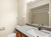 Thumbnail 7 of 9 - A bathroom with a toilet, sink, and mirror.