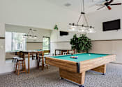 Thumbnail 17 of 43 - A pool table is in the middle of a room with a ceiling fan and a television mounted on the wall.