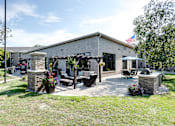 Thumbnail 29 of 43 - A building with a flag on top and a patio area with chairs and a table.