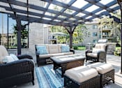 Thumbnail 26 of 43 - A patio with a black wicker couch and a white cushion.