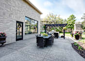 Thumbnail 24 of 43 - A patio with a table and chairs is surrounded by a brick wall.