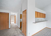 Thumbnail 40 of 60 - a living room with a kitchen and a door to a hallway