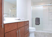 Thumbnail 23 of 31 - A white toilet sits in a bathroom with a walk-in shower.