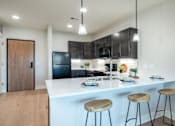 Thumbnail 2 of 18 - A kitchen with a white countertop and black cabinets.